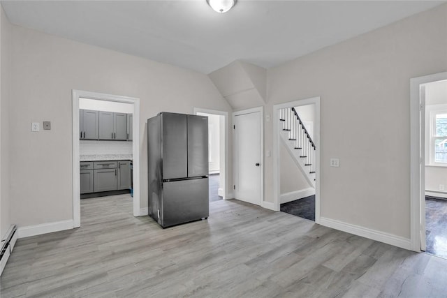 kitchen with freestanding refrigerator, light wood-style flooring, gray cabinets, baseboards, and vaulted ceiling