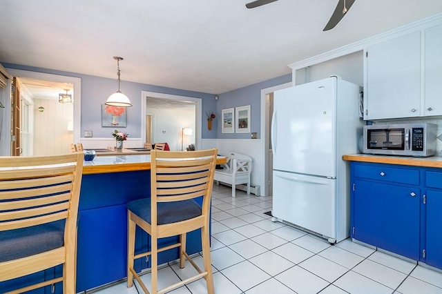 kitchen with freestanding refrigerator, stainless steel microwave, blue cabinets, ceiling fan, and light tile patterned floors