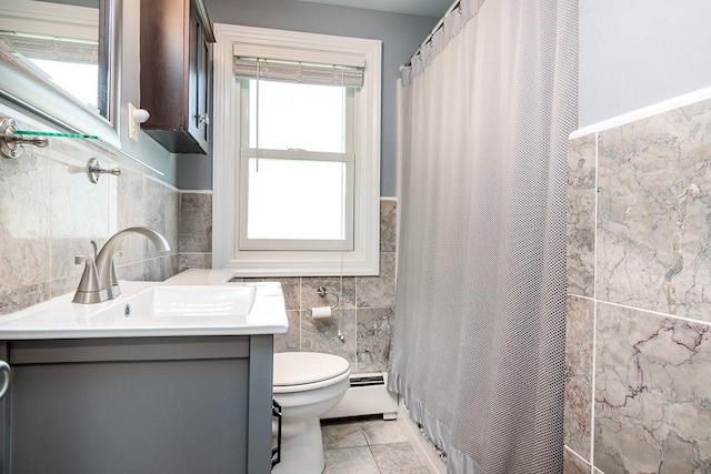 full bathroom with tile walls, baseboard heating, toilet, vanity, and wainscoting
