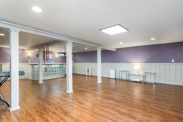 finished below grade area with a wainscoted wall, wood finished floors, recessed lighting, a community bar, and radiator heating unit