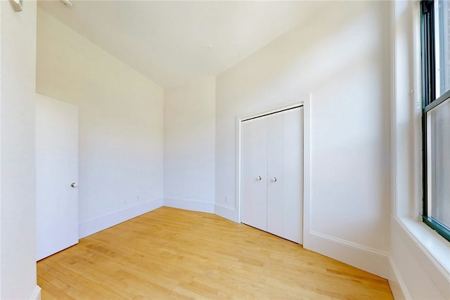 unfurnished bedroom with light wood finished floors and a closet