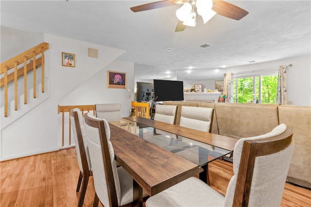 dining space featuring light wood-style floors, stairs, and a ceiling fan