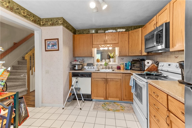 kitchen featuring white appliances, wallpapered walls, a sink, light countertops, and light tile patterned floors