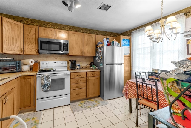 kitchen featuring stainless steel appliances, light countertops, a chandelier, light tile patterned floors, and backsplash