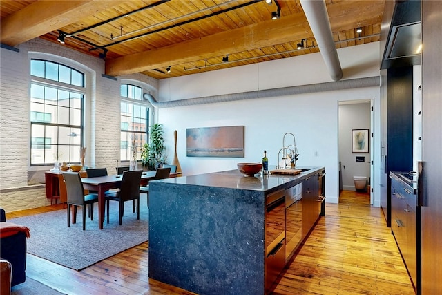 kitchen featuring wooden ceiling, a sink, light wood-style flooring, beam ceiling, and a kitchen island