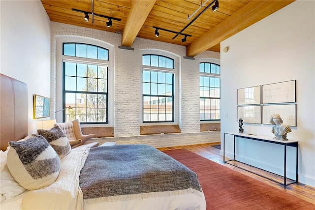 bedroom featuring track lighting, wood ceiling, wood finished floors, and beam ceiling