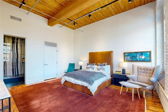 bedroom featuring wooden ceiling, wood finished floors, beamed ceiling, and a high ceiling