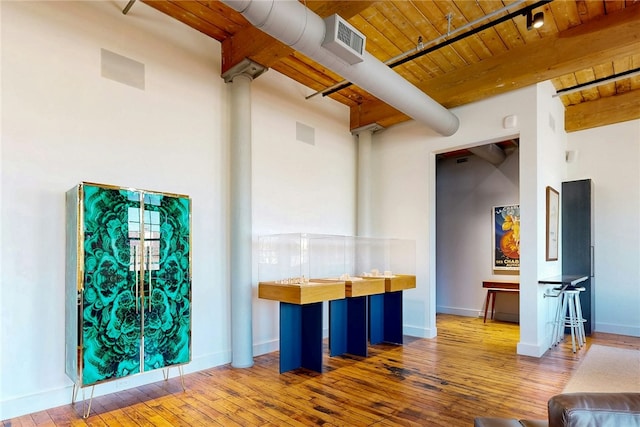 misc room featuring beamed ceiling, wood ceiling, wood-type flooring, and baseboards