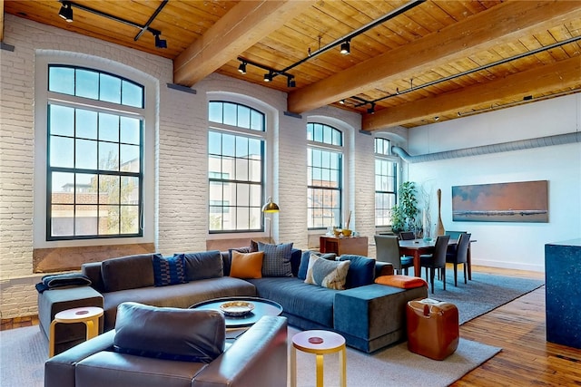 living room featuring track lighting, wooden ceiling, brick wall, wood-type flooring, and baseboards