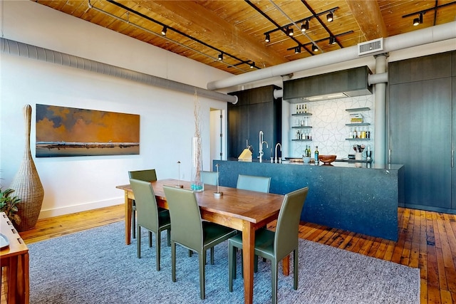dining room featuring track lighting, wooden ceiling, wood-type flooring, baseboards, and beam ceiling
