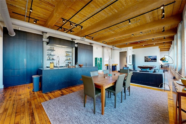 dining space featuring track lighting, hardwood / wood-style flooring, wooden ceiling, and beam ceiling
