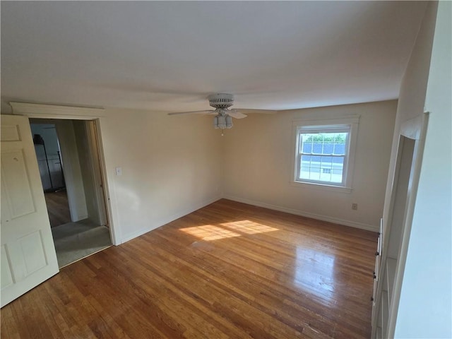 unfurnished room with wood finished floors, a ceiling fan, and baseboards