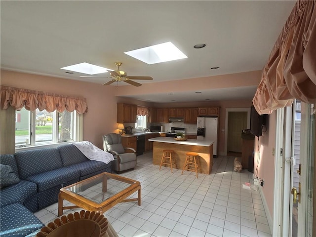 living area with a skylight, light tile patterned floors, and plenty of natural light