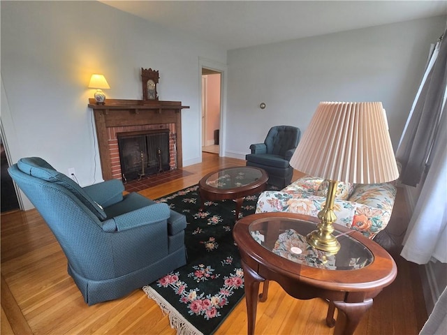 living room with a brick fireplace and wood finished floors