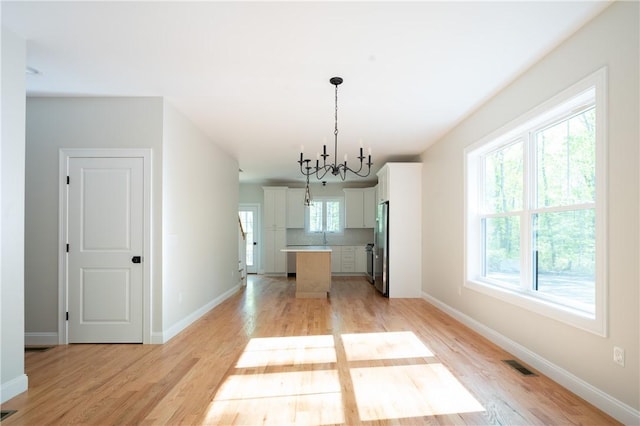 145 Wolf Rock Rd, Exeter, RI 02822 - unfurnished dining area featuring light wood-style floors, baseboards, and a chandelier