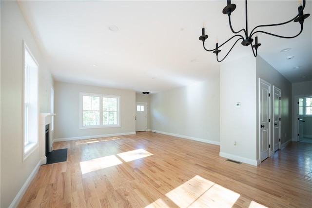 145 Wolf Rock Rd, Exeter, RI 02822 - unfurnished living room featuring a chandelier, light wood finished floors, baseboards, and a fireplace with flush hearth