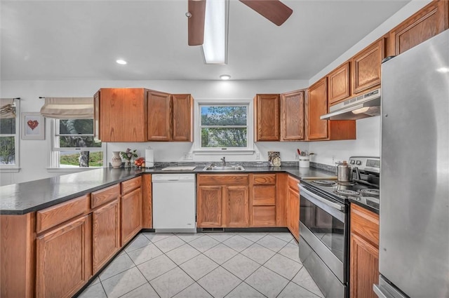 kitchen featuring stainless steel appliances, under cabinet range hood, dark countertops, a peninsula, and recessed lighting