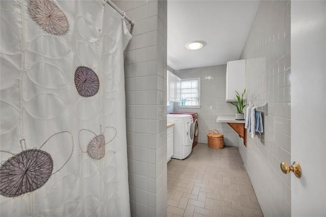 full bathroom with tile walls, brick patterned flooring, a shower with curtain, and washer and dryer