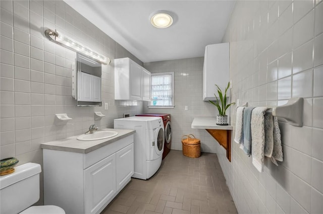 bathroom featuring independent washer and dryer, tile walls, toilet, brick patterned flooring, and vanity
