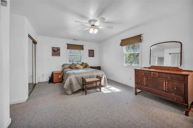 carpeted bedroom with multiple windows, baseboards, and a ceiling fan