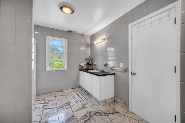 bathroom with tile walls, vanity, and marble finish floors