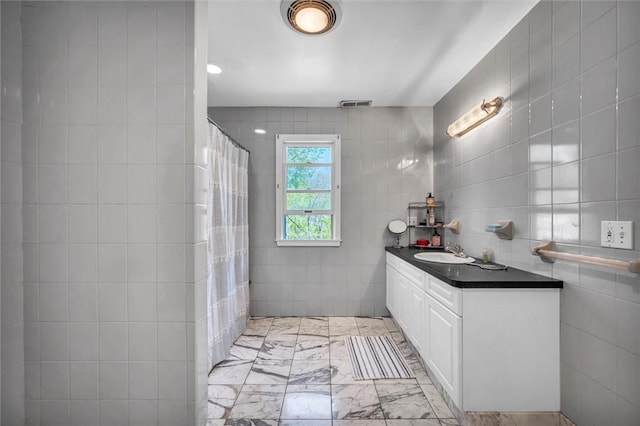 bathroom with tile walls, vanity, marble finish floors, and a shower with curtain