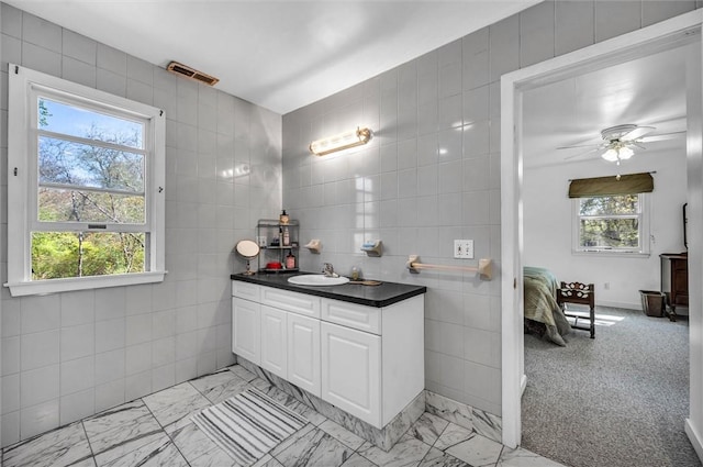 bathroom with tile walls, vanity, marble finish floors, ceiling fan, and ensuite bathroom