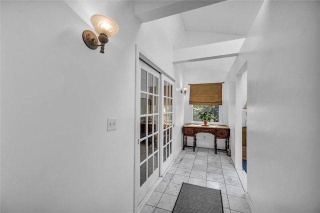 hall with light marble finish floors and vaulted ceiling