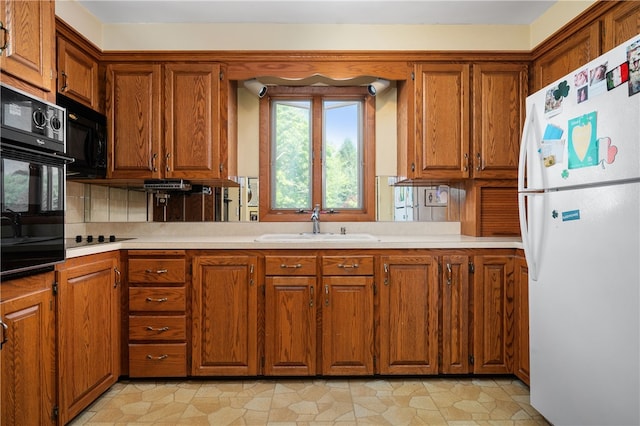 kitchen with black appliances, a sink, brown cabinetry, and light countertops