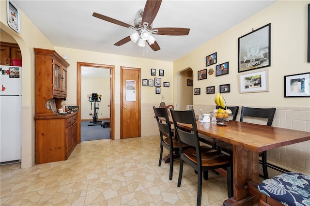 dining space featuring arched walkways and a ceiling fan