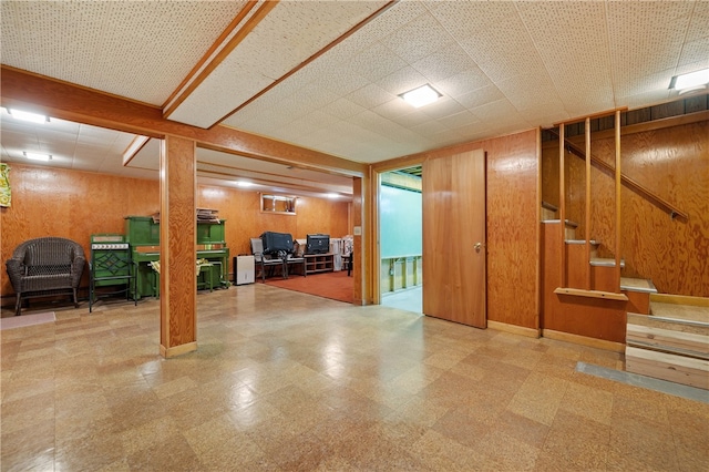 finished basement with tile patterned floors, wood walls, and stairway