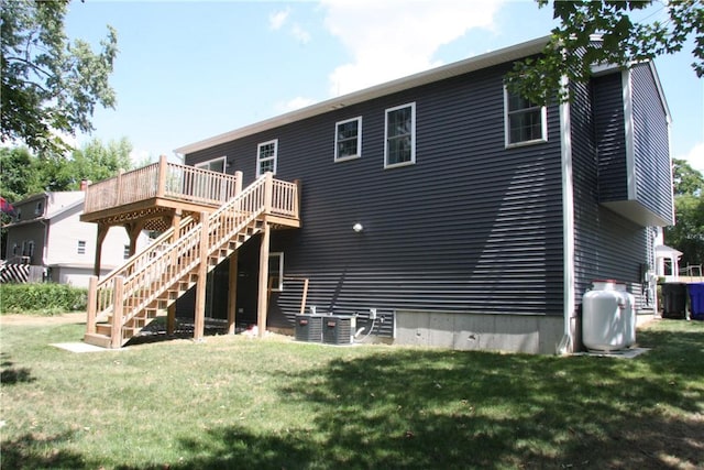 back of house featuring stairs, a deck, and a lawn