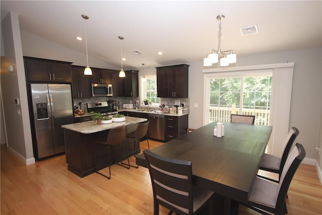 dining room featuring light wood-type flooring, a chandelier, vaulted ceiling, recessed lighting, and baseboards