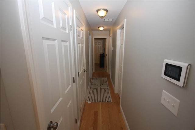 hall featuring light wood finished floors and baseboards