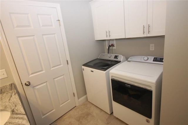 clothes washing area featuring washer and clothes dryer, cabinet space, light tile patterned floors, and baseboards