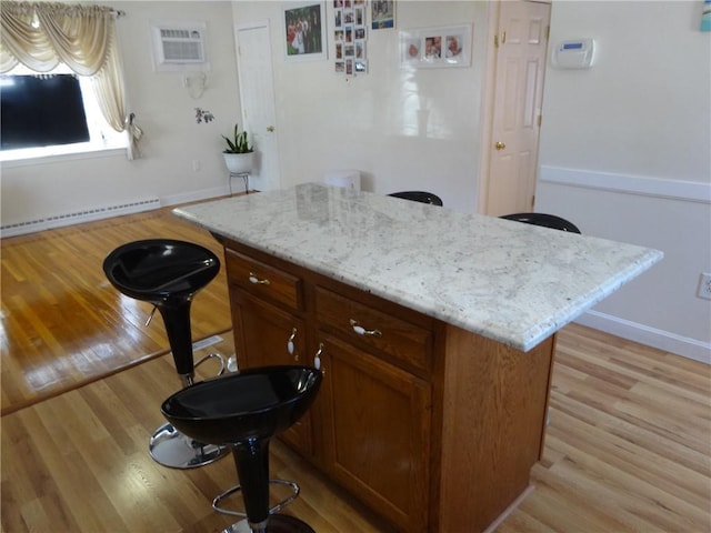 kitchen featuring a baseboard radiator, a wall mounted AC, and light wood-style floors