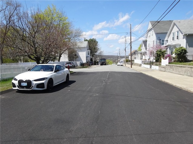 view of asphalt road with a residential view, curbs, and sidewalks