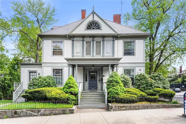 view of front of house featuring a chimney and fence