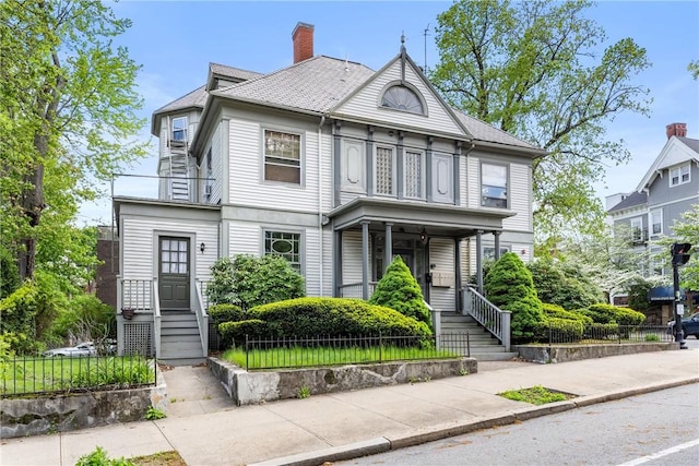 victorian house featuring a porch and a chimney