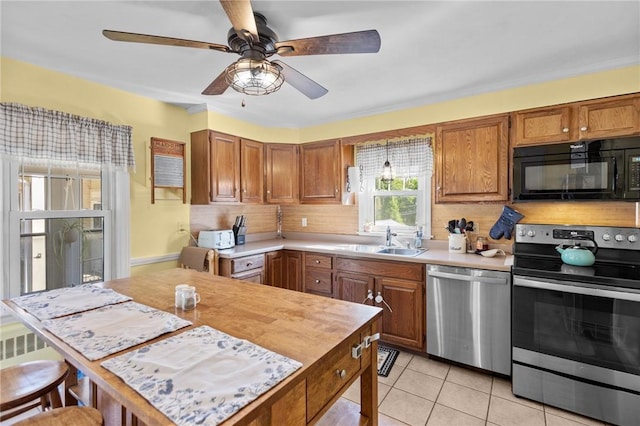 kitchen with appliances with stainless steel finishes, a sink, light countertops, brown cabinets, and backsplash