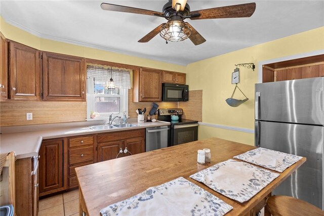 kitchen with appliances with stainless steel finishes, a sink, light countertops, and ceiling fan