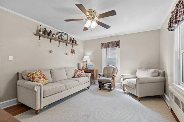 living room featuring radiator heating unit, a ceiling fan, crown molding, and baseboards