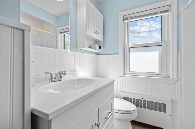 full bath with radiator heating unit, a wainscoted wall, toilet, vanity, and a shower