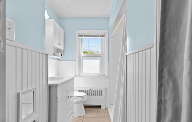 bathroom with radiator heating unit, toilet, wainscoting, tile patterned flooring, and vanity
