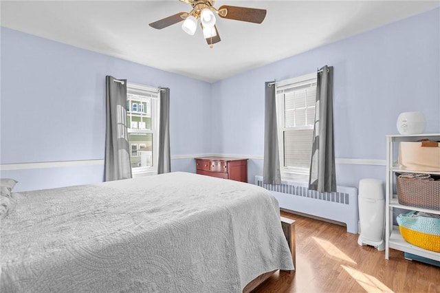 bedroom featuring radiator heating unit, wood finished floors, and a ceiling fan