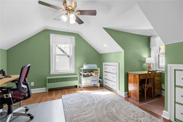 office space featuring radiator heating unit, wood finished floors, a ceiling fan, plenty of natural light, and lofted ceiling