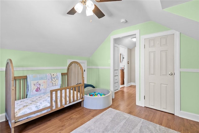 bedroom with lofted ceiling, wood finished floors, baseboards, and ceiling fan