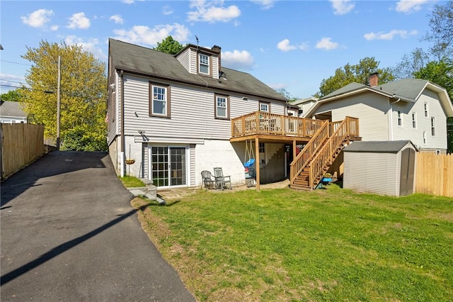 rear view of house featuring stairs, a wooden deck, a shed, an outdoor structure, and a chimney
