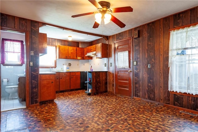 49 Gooding St, Pawtucket, RI 02860 - kitchen with under cabinet range hood, wooden walls, a ceiling fan, and brown cabinetry