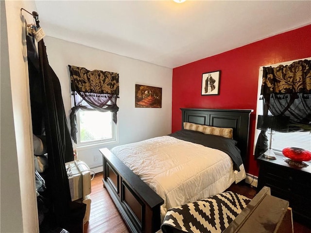 bedroom featuring wood finished floors, a baseboard heating unit, and baseboard heating